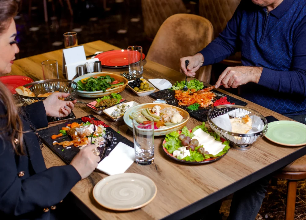 couple-have-dinner-with-pasta-salads-cheese-plate-pickles-olives.jpg.